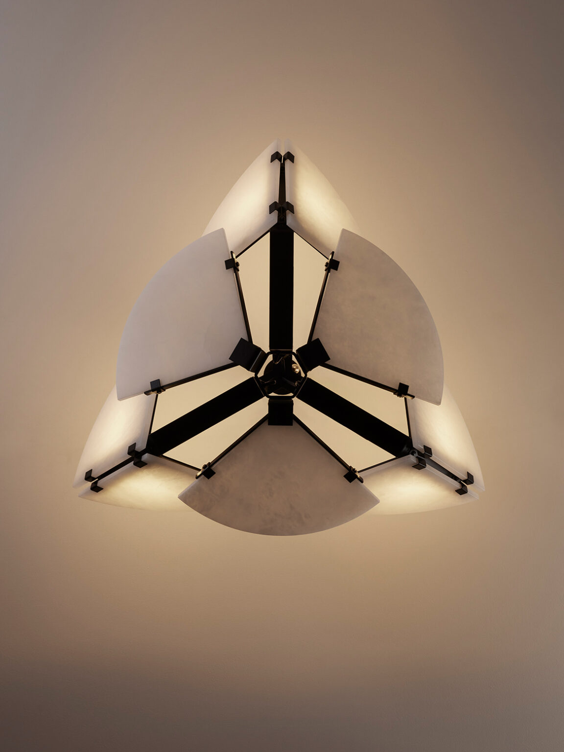 Mcde-sus-102a-005-1152x1536 | rewire Modern ceiling light fixture with white curved panels forming a geometric star-like shape, emitting warm light from its center.