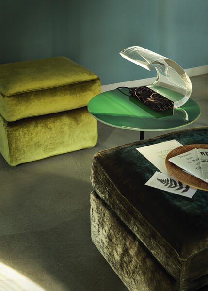 arched acrylic table lamp with marble base on a side table next to luxurious green velvet ottomans