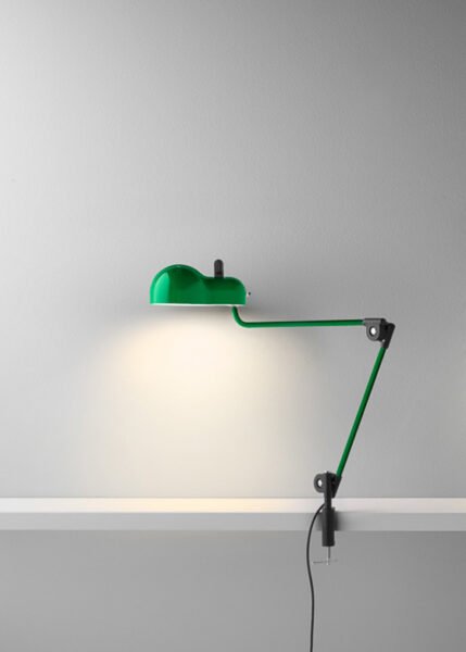 Topo lamp on a white background. The lamp has a metal shell with slits and a lampshade that corresponds to the classic E27 bulb casing. It has jointed metal arms for extending or retracting and is available in various finishes.