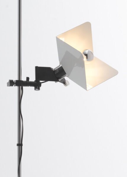 Image of a modern Triedro Floor Lamp with a contoured metal lampshade made of three parts. The lamp features a double joint that allows the light source to be rotated and adjusted flexibly. Available in white, black, or chrome finish.