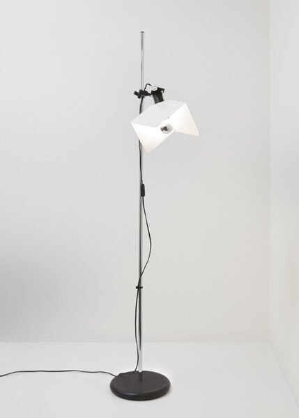 Image of a modern Triedro Floor Lamp with a contoured metal lampshade made of three parts. The lamp features a double joint that allows the light source to be rotated and adjusted flexibly. Available in white, black, or chrome finish.