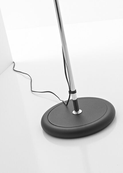 Image of a modern Triedro Floor Lamp with a contoured metal lampshade made of three parts. The lamp features a double joint that allows the light source to be rotated and adjusted flexibly. Available in white, black, or chrome finish.