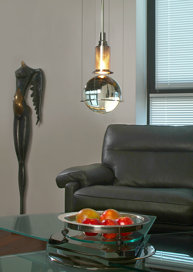 Hl3s81-ambiente_web_2 | rewire Sleek living room with a glass coffee table, a bowl of apples, a black leather sofa, and a warm pendant light hanging from the ceiling.