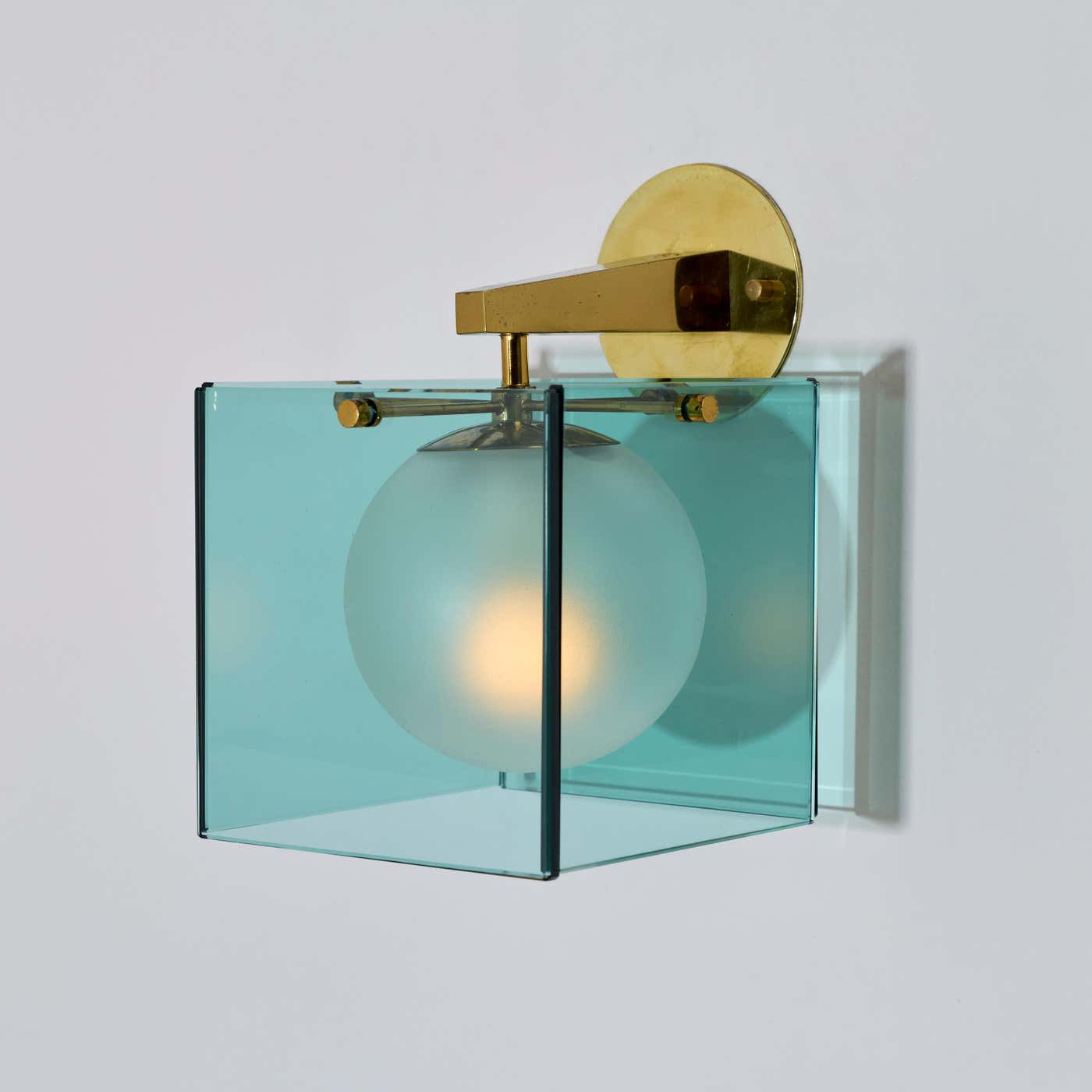 translucent aquamarine glass cube over glove with brass arm