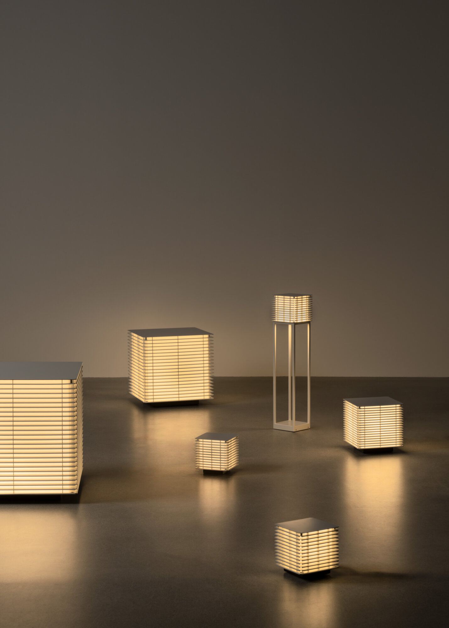 2 | rewire Decorative set of warm-lit slatted lamps in various rectangular and cube shapes on a dark floor.