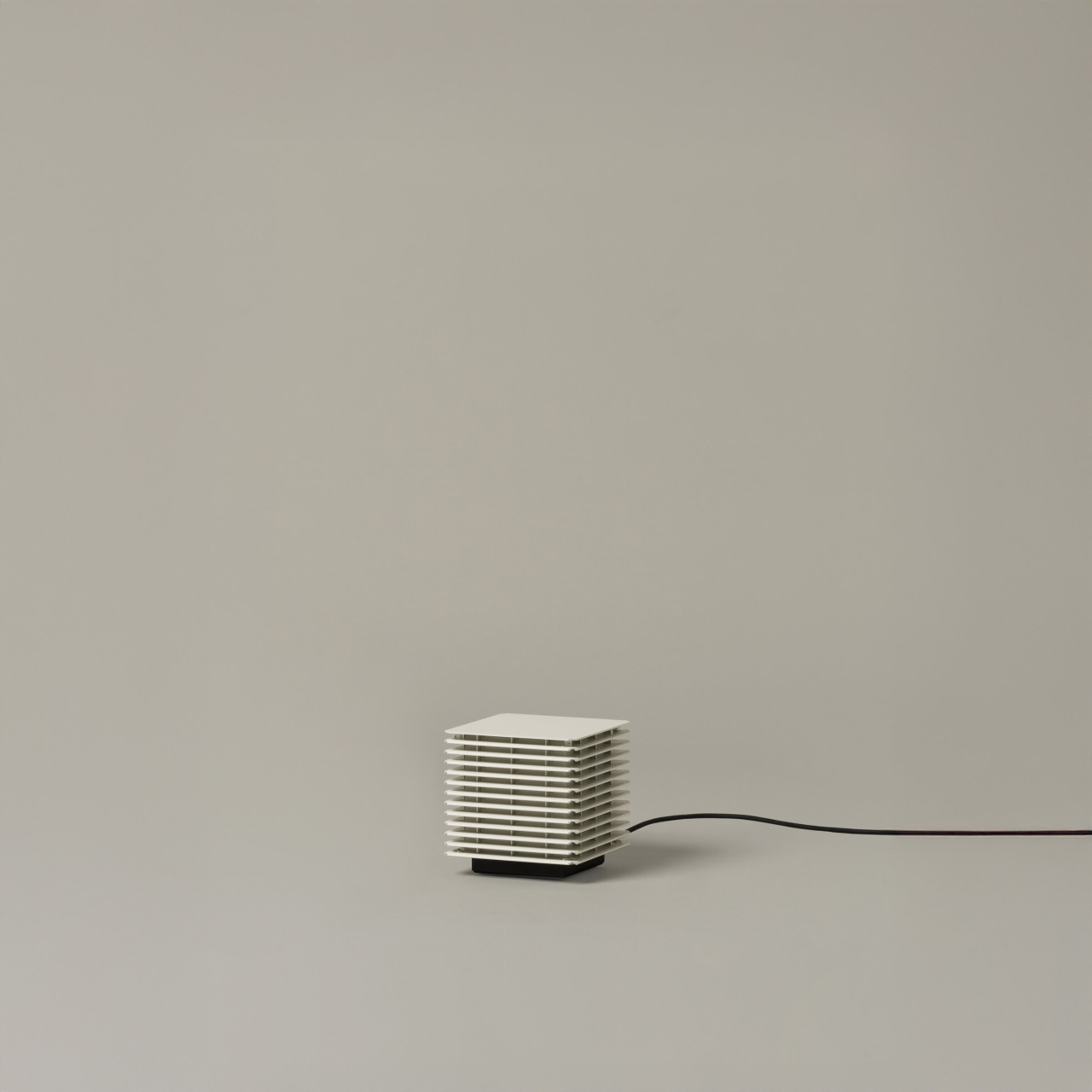 2 | rewire Small white, vented cube heater on a black base with a cord extending to the right on a neutral background.