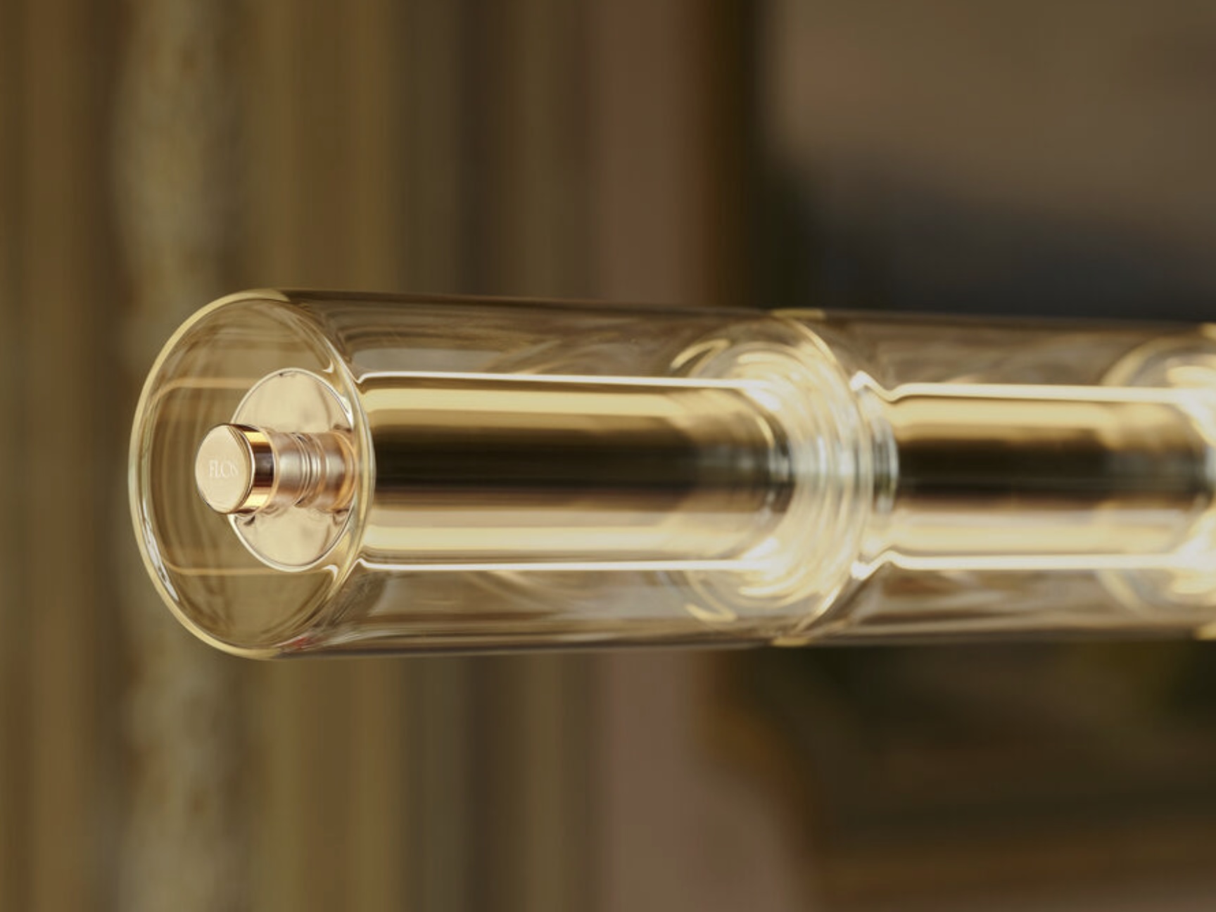 Screenshot | rewire Close-up of a glass light bulb or filament tube with a gold-toned inner cap and warm reflections across the glass.