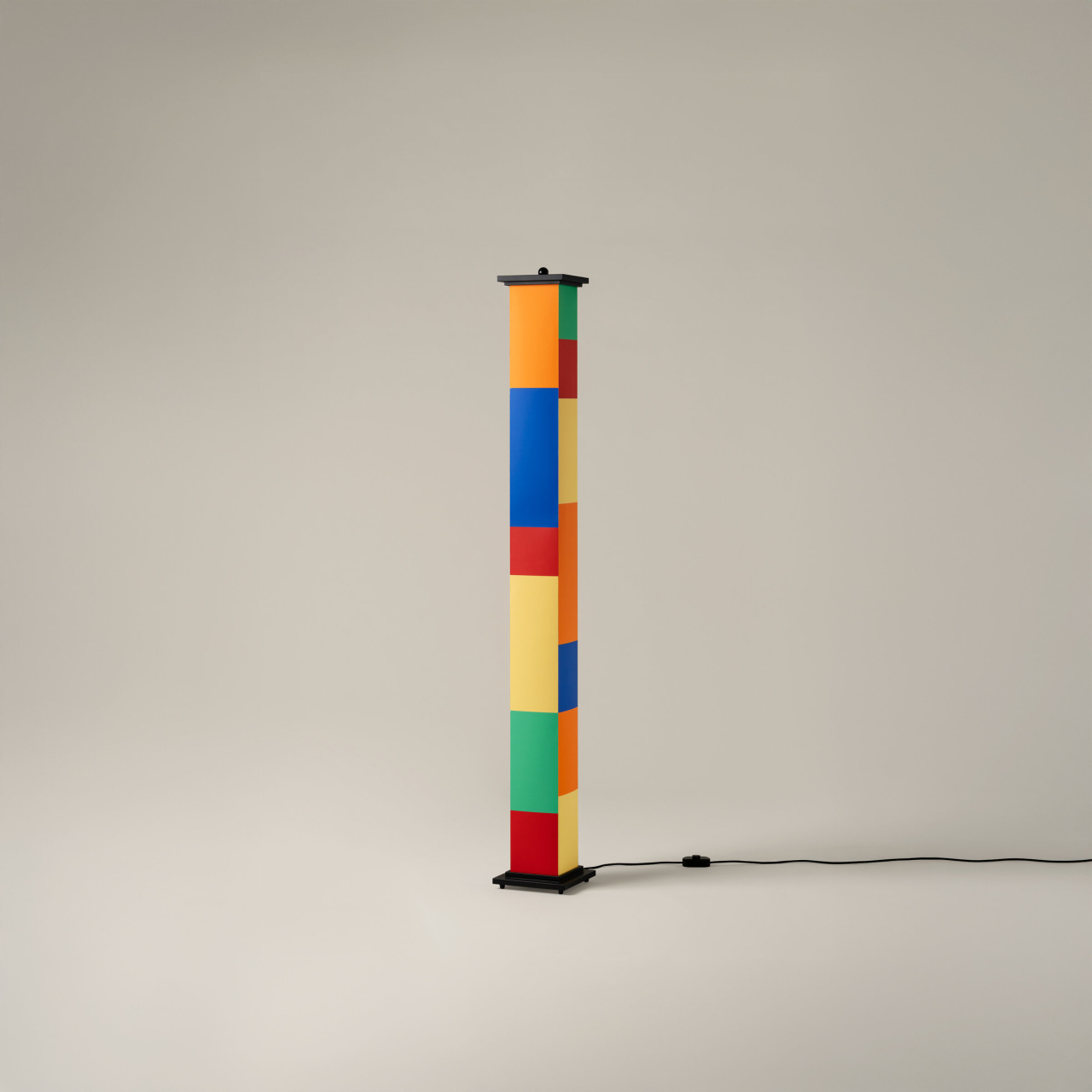 La-bella-durmiente-enric-badrinas-2024-18-off-r25-x2400-1280x1280 | rewire Tall column of multicolored blocks stacked on a black pedestal, with a power cord trailing to the right.