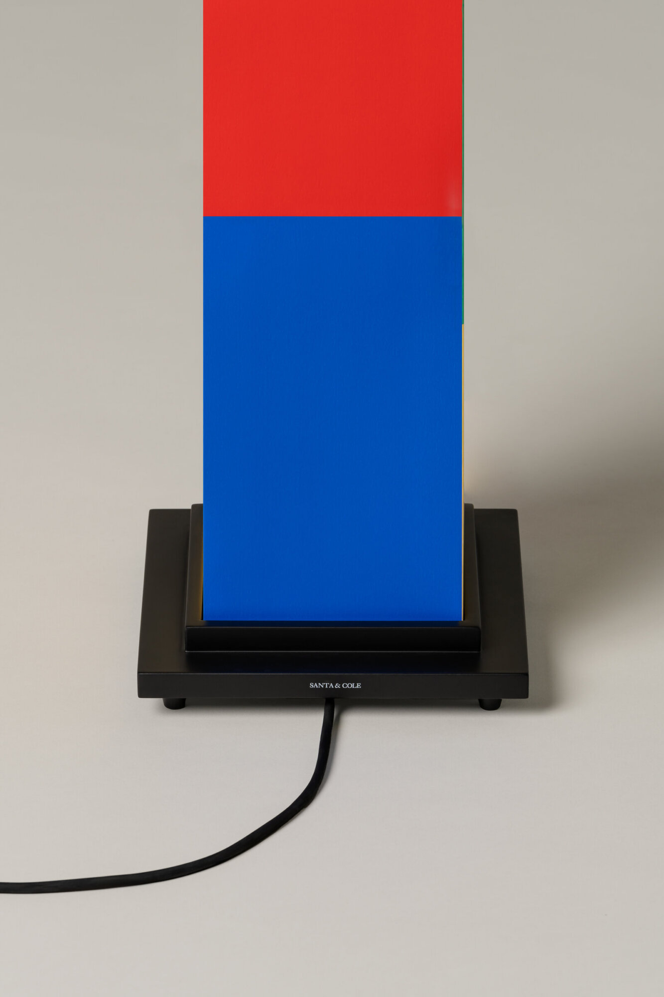 La-bella-durmiente-enric-badrinas-2024-23-det-x2400 | rewire Tall vertical color-block sculpture: red upper half, blue lower half, on a black display stand with a cord visible; Santa & Cole branding on the base.