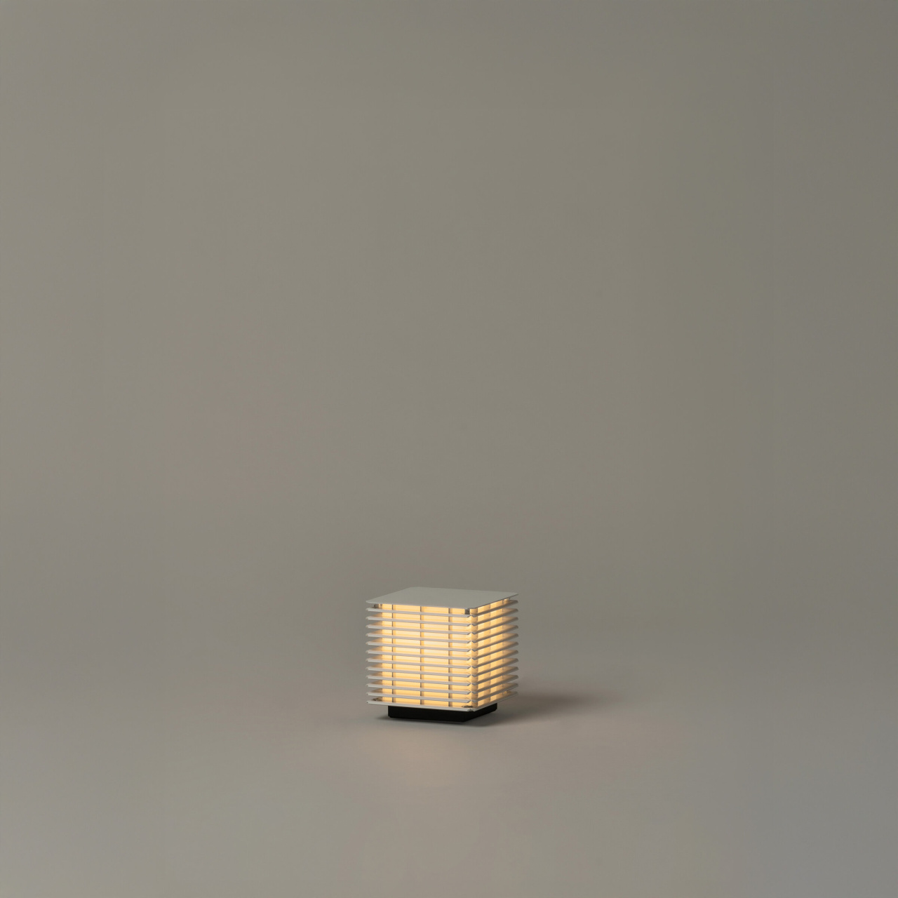 Shiro171 | rewire Small square table lamp with horizontal slats casting a warm glow on a neutral floor.