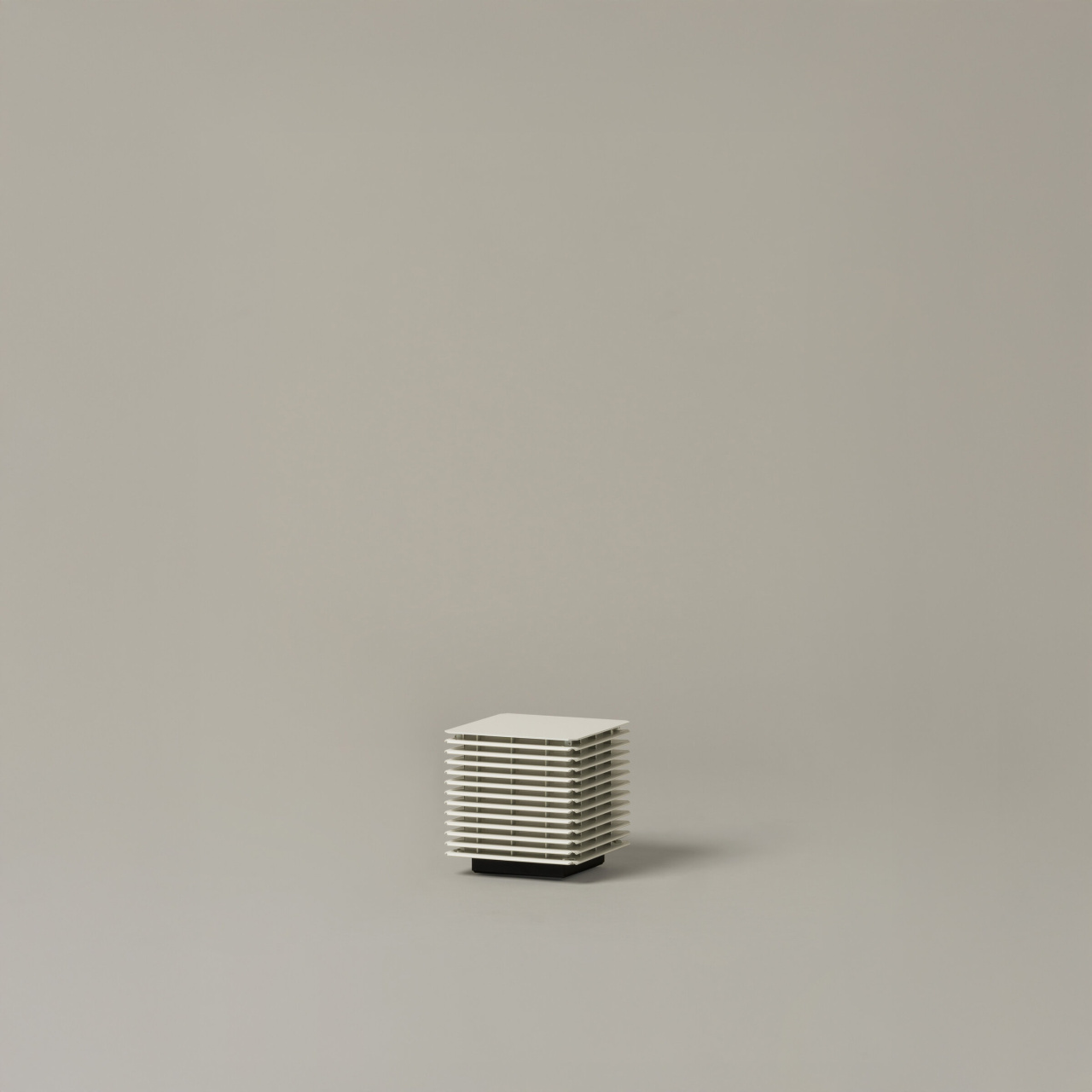 Shiro172 | rewire Compact white, slatted square heater on a small black base against a neutral beige background, shown from the side.
