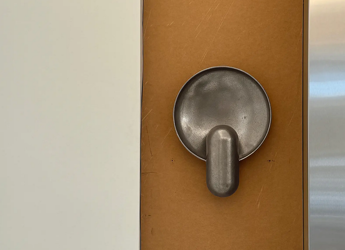 Top-down view of a gray metal frying pan mounted on a brown surface, with the handle pointing downward.