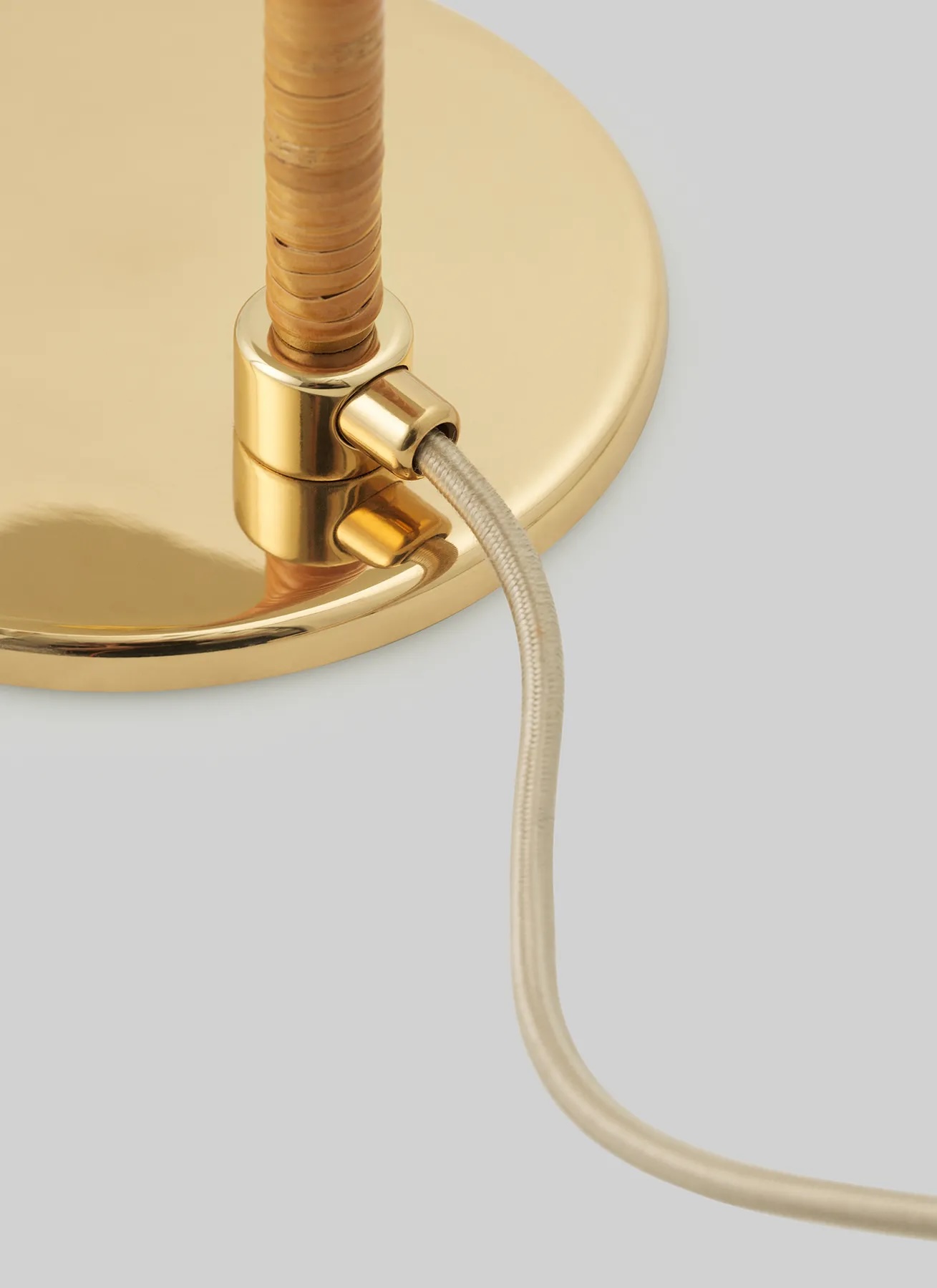 10003869_c2_9602+floor+lamp_brass_wicker+willow | rewire Close-up of a gold metal lamp base with a braided cord connected to the switch area for electrical wiring.