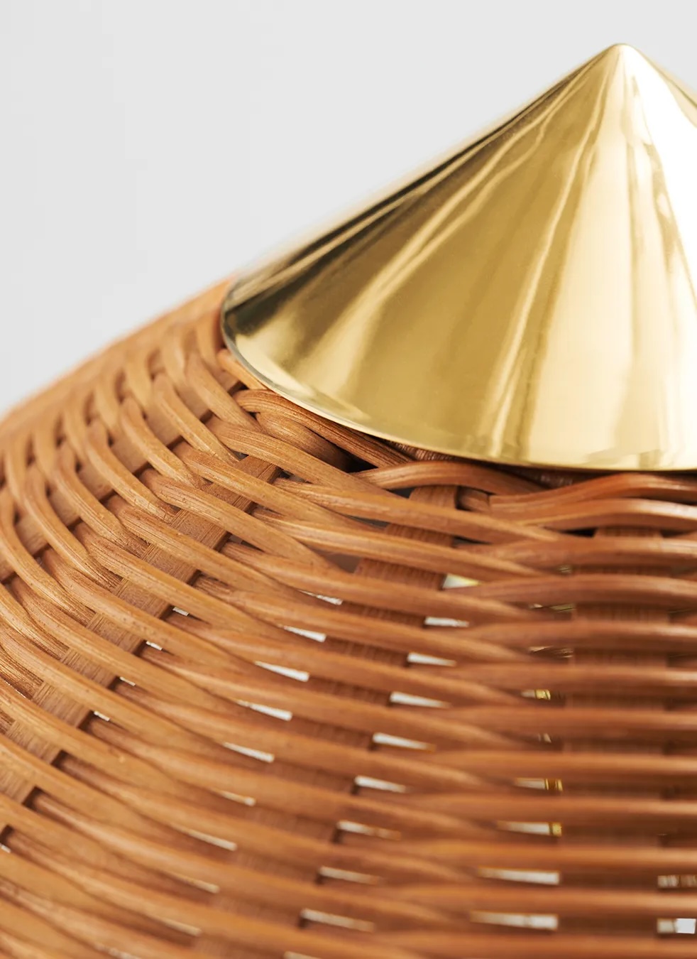 10003869_c_9602+floor+lamp_brass_wicker+willow | rewire Close-up of a woven wicker lampshade with a shiny gold metal cone on top.
